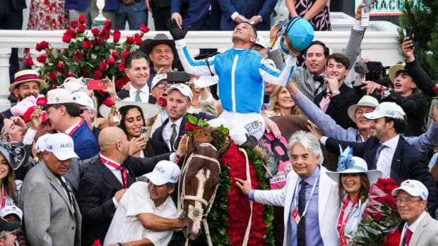 Jockey Javier Castellano celebrates aboard Mage in the Winner's Circle as trainer Gustavo Delgado Sr. puts a hand on the garland of roses after the 149th Kentucky Derby